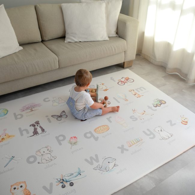 Child sitting on a Afrikaans Alphabet play mat