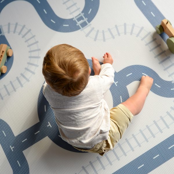 Boy sitting on a car track play mat