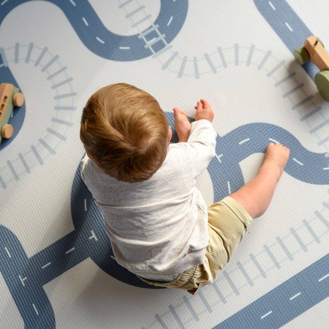 Boy sitting on a car track play mat